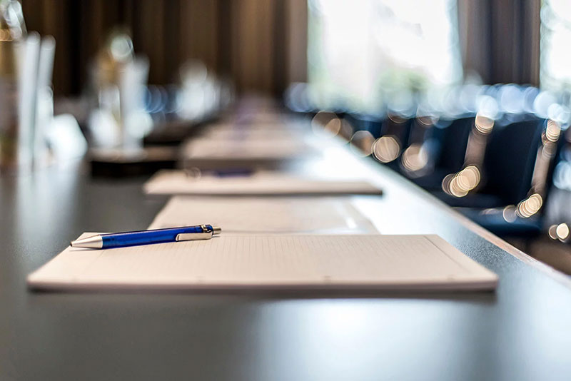 Conference table with stack of papers and pen