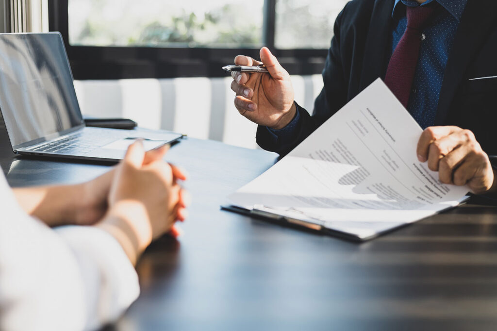 Two real estate agents sitting at a table reviewing contracts.