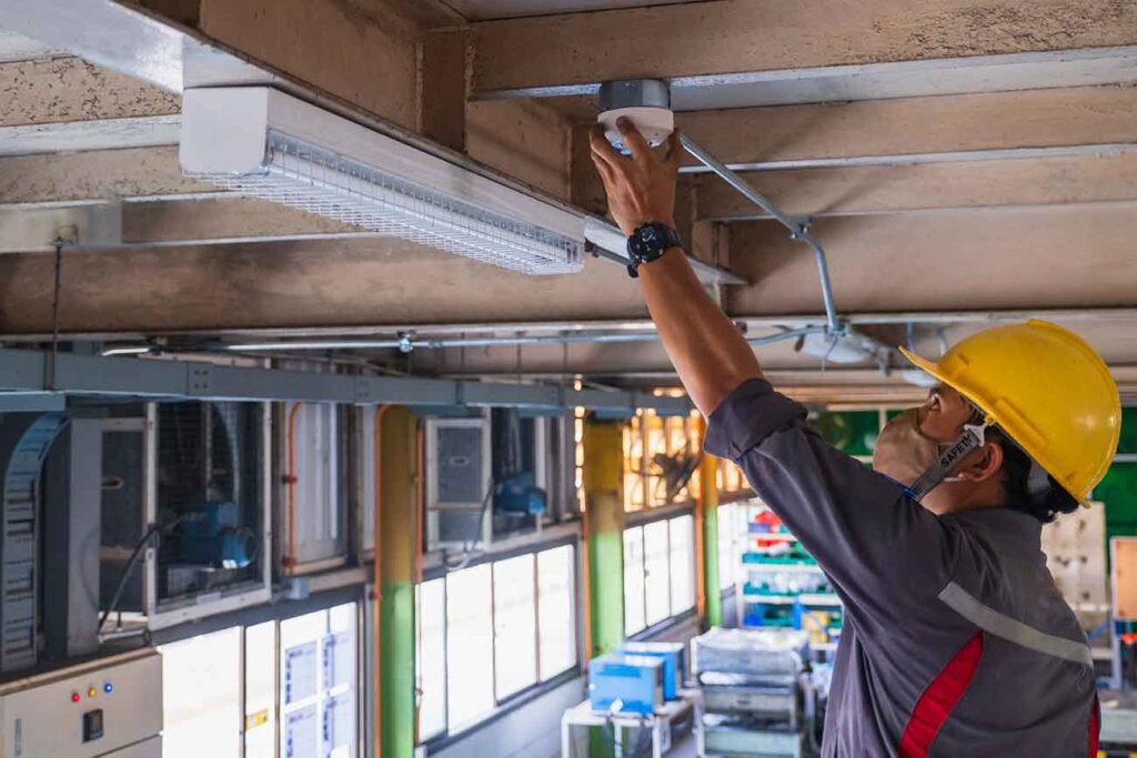 Florida electrician installing a light fixture in a new construction office building