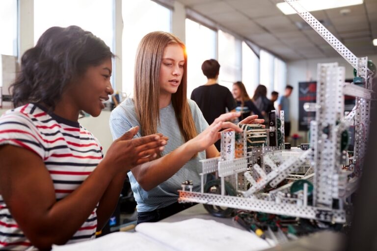 Two Female College Students Building Machine In Science Robotics